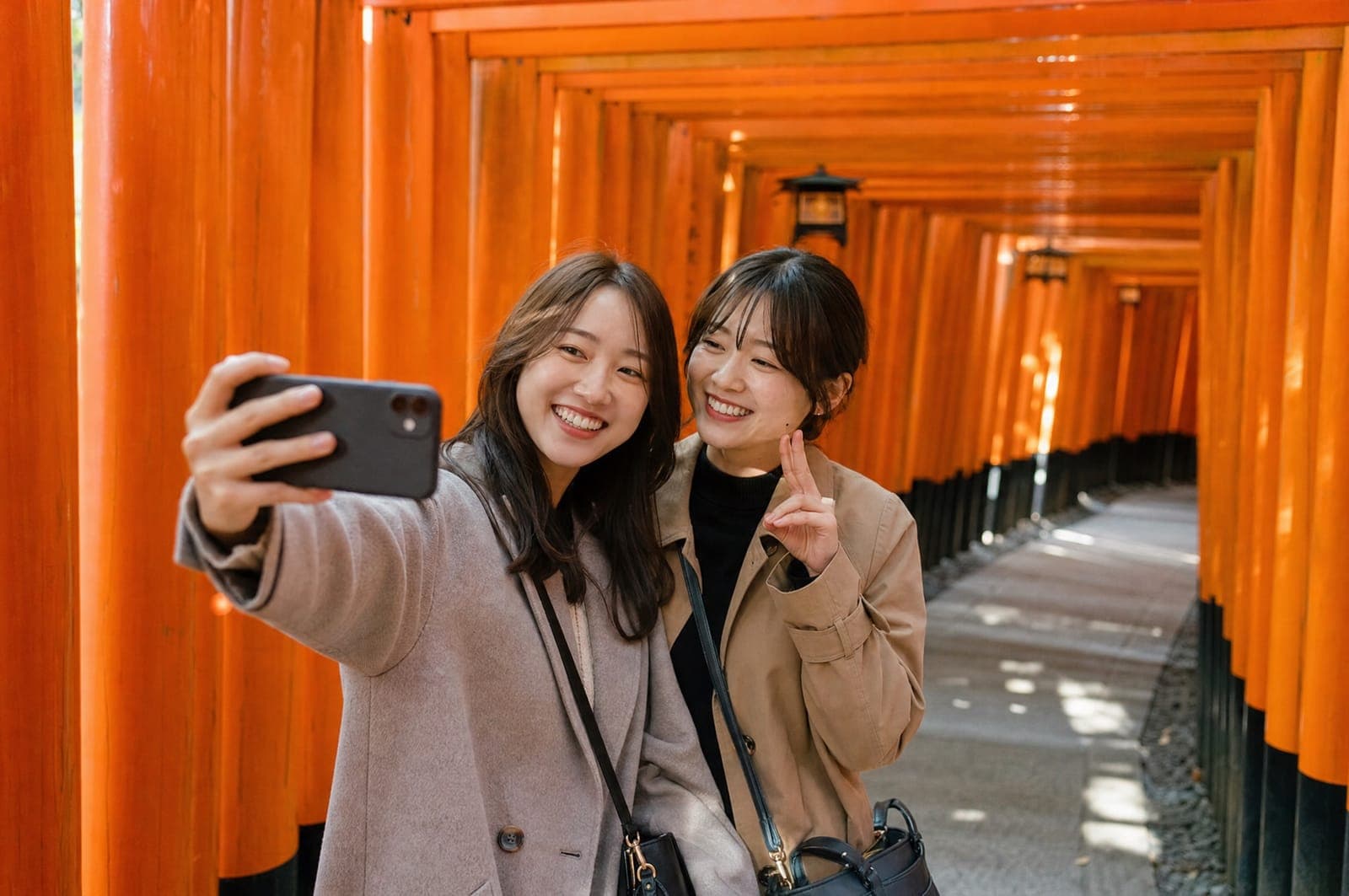 Two friends taking a selfie in the tunnel of torii gates at Fushimi Inari